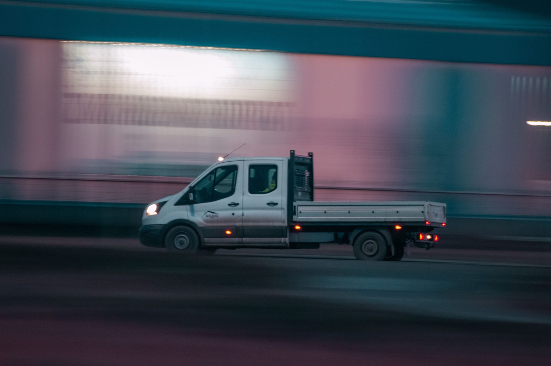 Long exposure shot of a pickup truck moving swiftly at night, capturing motion and urban energy.