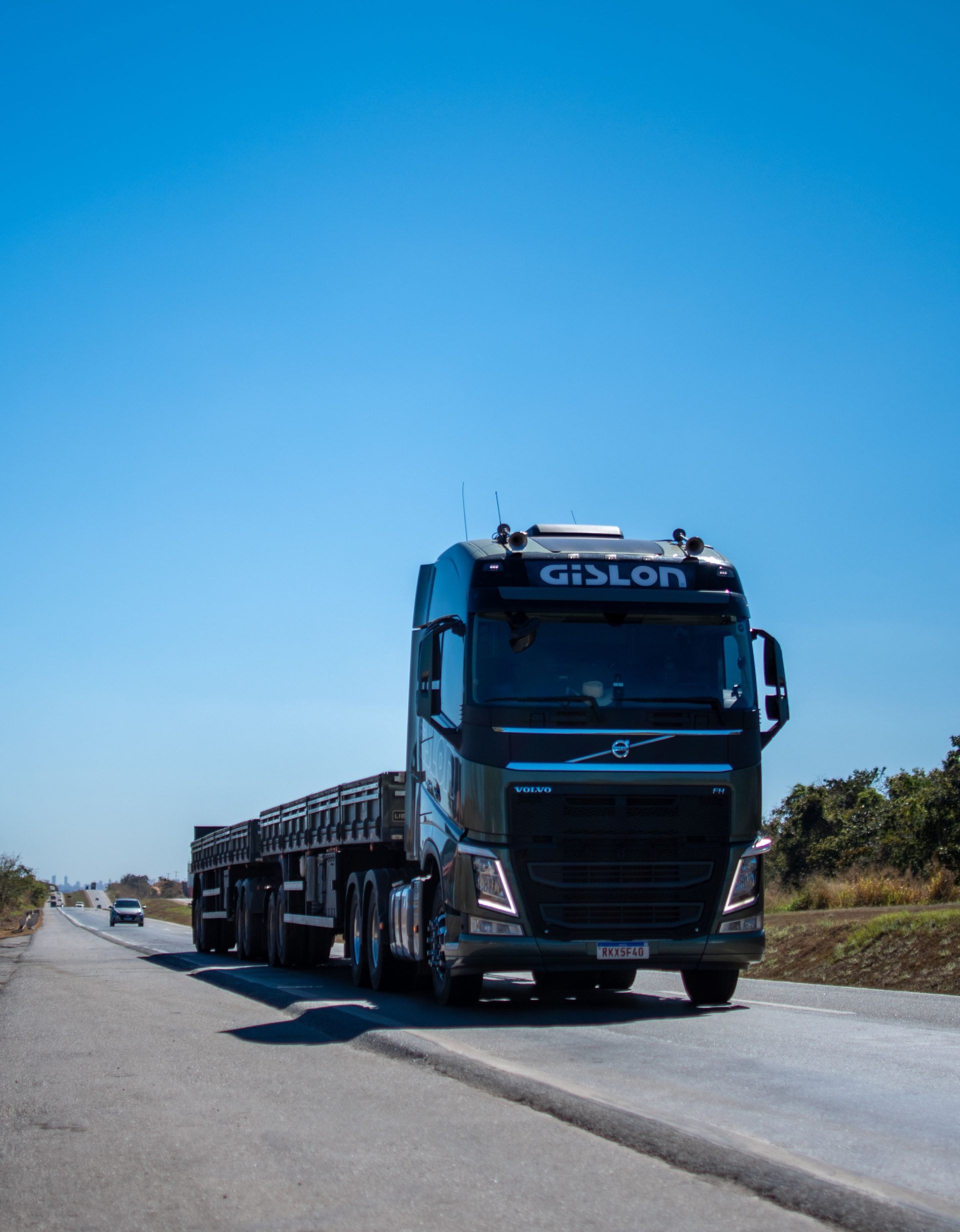 A black truck travels on a sunny highway in Brazil under clear blue skies.